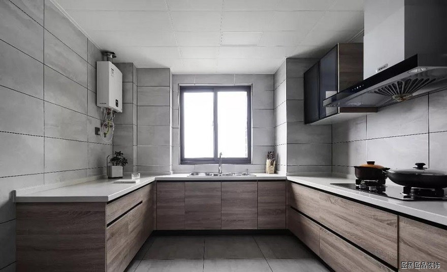 廚房是選擇了灰色和木色的結合，灰色的啞光磚看起來簡潔又(yòu)舒适，木質的櫥櫃又(yòu)能帶來一(yī)些溫馨感，牆面留空大(dà)部分(fēn)不做櫃子，避免太過壓抑。

