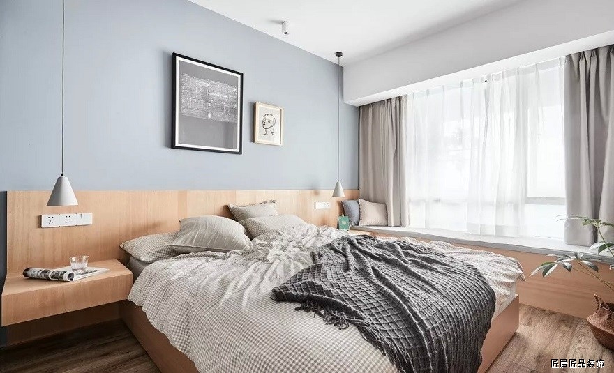 主卧的床頭櫃、床靠背和飄窗是一(yī)體(tǐ)化設計，配合MUJI無靠背收納床，整體(tǐ)風格清新簡約。淺灰色的背景牆和水泥燈稍稍添了些清冷氣息。